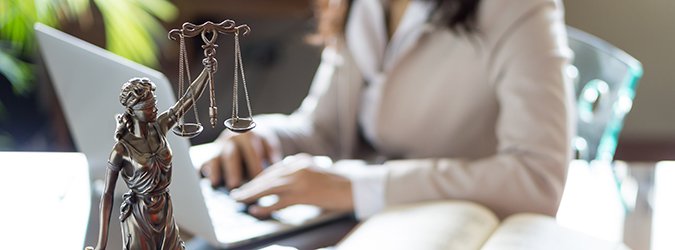 Lawyer office. Statue of Justice with scales and lawyer working on a laptop. Legal law, advice and justice concept